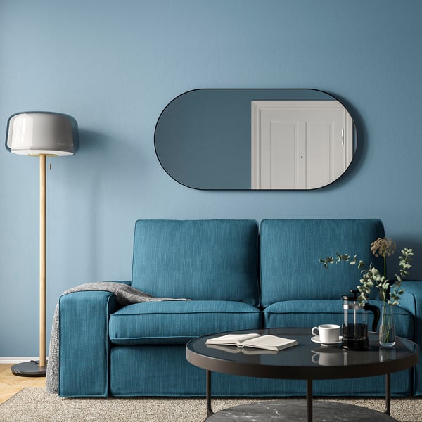 Modern living room with blue sofa, LINDBYN mirror, coffee table, and floor lamp.