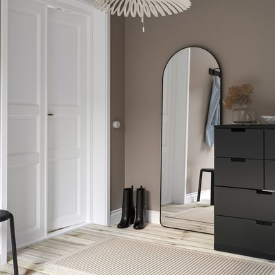 LINDBYN mirror, black frame on beige wall, reflects door, near dresser & boots, stylish light.