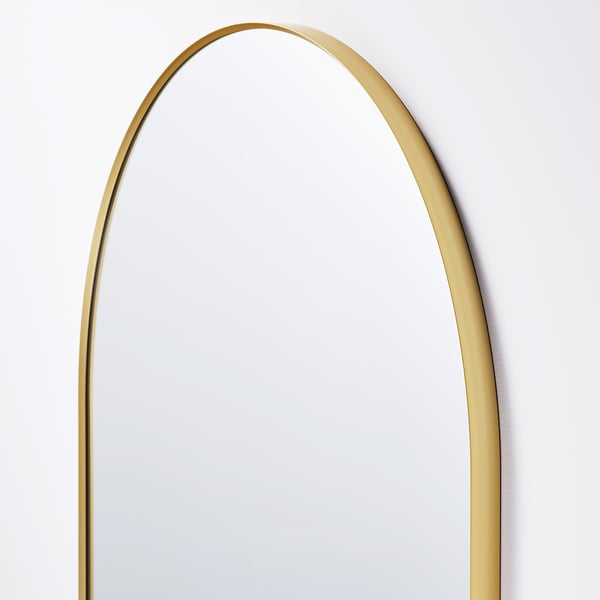 Large, elegant mirror with golden frame, round top, reflecting a plain surface. Shines with quality and style.
