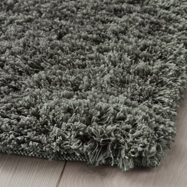 Plush grey area rug with soft, thick pile on wooden floor, machine washable, dense for noise reduction.