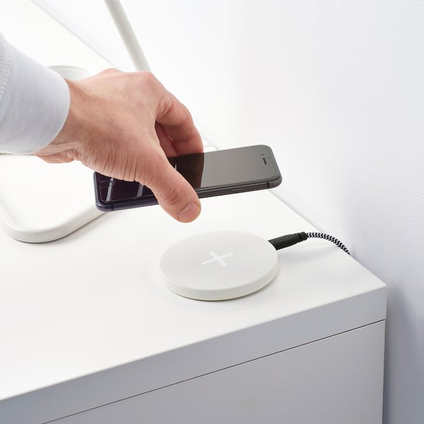 Person placing smartphone on LIVBOJ wireless charging pad, showing wireless charging setup.