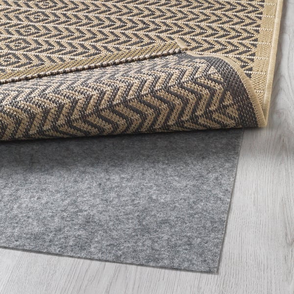 Dark and light grey patterned rug with a black and tan zigzag border and a grey felt rug underlay for anti-slip safety.