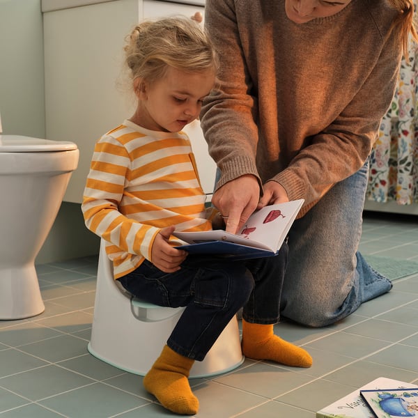 Girl learns to use toilet with adults help.