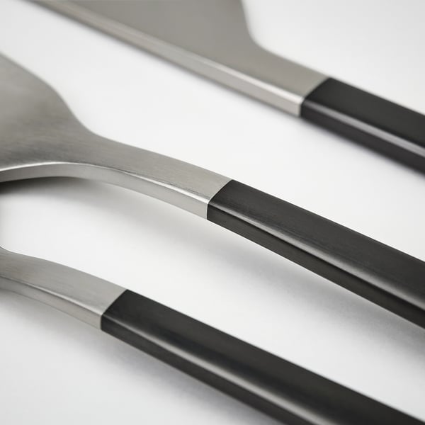 Four pieces of modern stainless steel cutlery, featuring sleek lines and comfortable handles, arranged neatly.