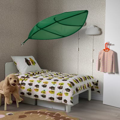 Kids bedroom with leafy LÖVA bed canopy, bear/sun patterns, stuffed dog toy.