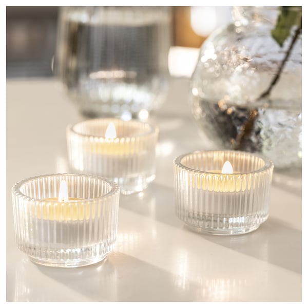 Three lit ribbed glass candles on a table, creating a warm, inviting ambiance.