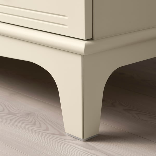 Modern storage unit with smooth, cream-colored finish and curved legs on wooden floor.