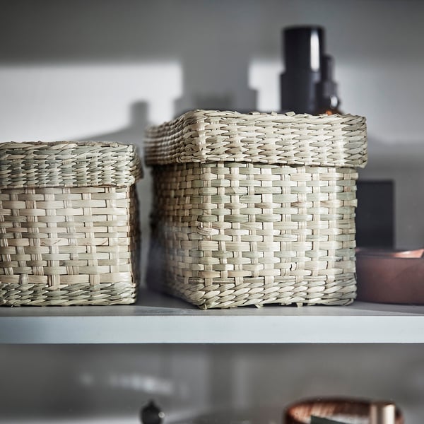 Two woven seagrass baskets on a white shelf, neatly organised.