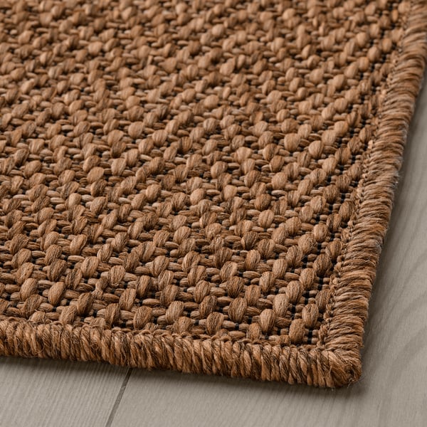 Natural woven rug, flat-woven, rustic look, durable material, on wooden floor.