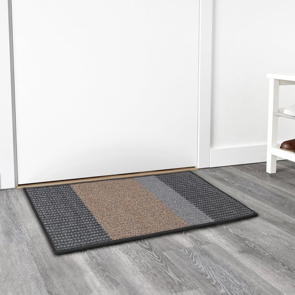 Textured striped door mat on wooden floor, weather-resistant, keeps floors clean.