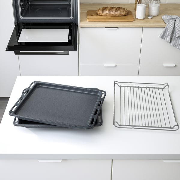 Modern kitchen with oven, trays, and bread. Oven door open, showing trays ready for baking.