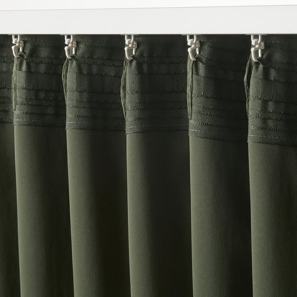 Dark green curtains hung using metal hooks, showcasing block-out fabric and pleated design for light control and privacy.