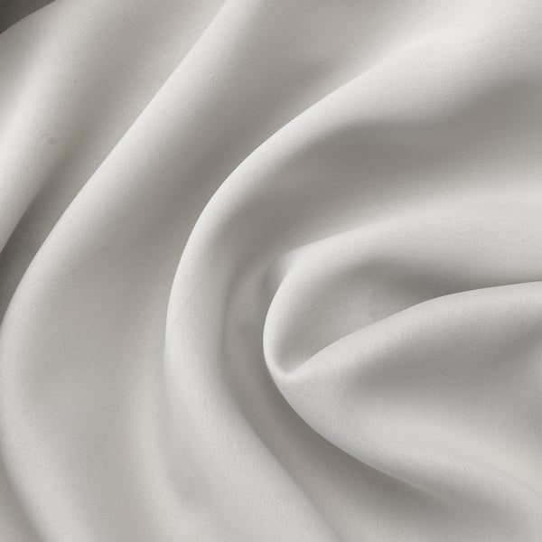 Folded white curtains close-up, smooth texture, showing quality fabric.