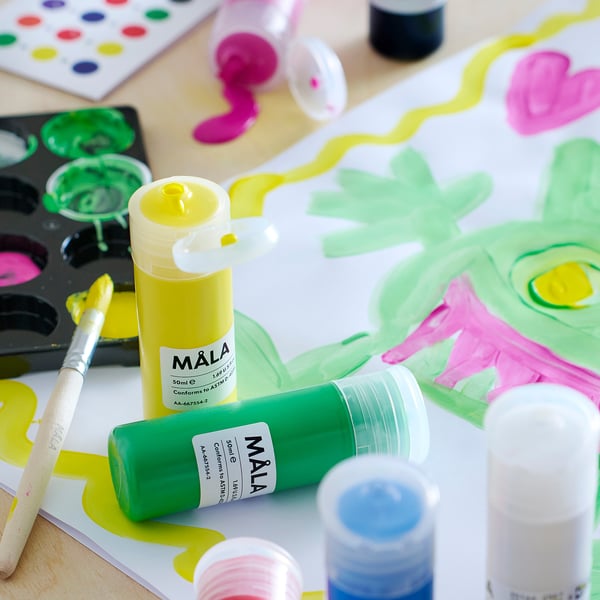 Art supplies: squeeze bottles of yellow and green MÅLA paint, brush, and colourful painting.