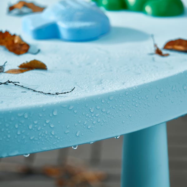 Light blue childrens table with water droplets, leaves, and partial seating.