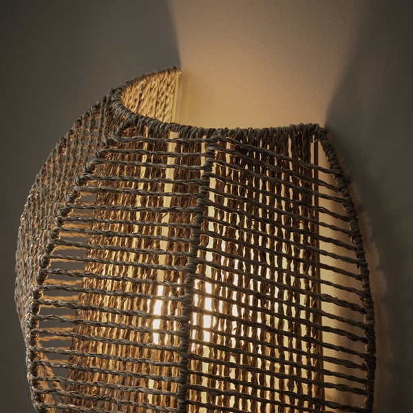 Hand-braided wall lamp with natural sedge material, emitting warm decorative light.