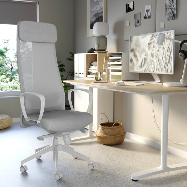 Modern home office with light grey MARKUS office chair, wooden desk, monitor, lamp, and decorative items.