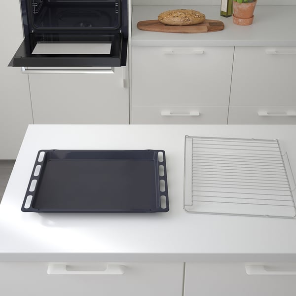 Modern kitchen with built-in oven and black baking tray, wire rack, and bread on counter.