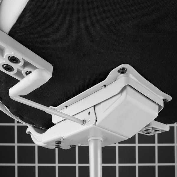 Close-up of MATCHSPEL chair mechanism. White plastic parts, metal pole, and textured black fabric. Shows quality construction.