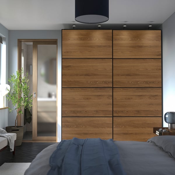 Modern bedroom with tall MEHAMN wardrobes, blue bedding, and indoor plant.