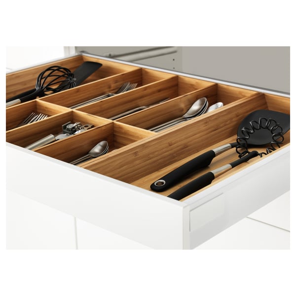 Open kitchen drawer with wooden compartments. Utensils organised in sections. Self-closing feature visible.