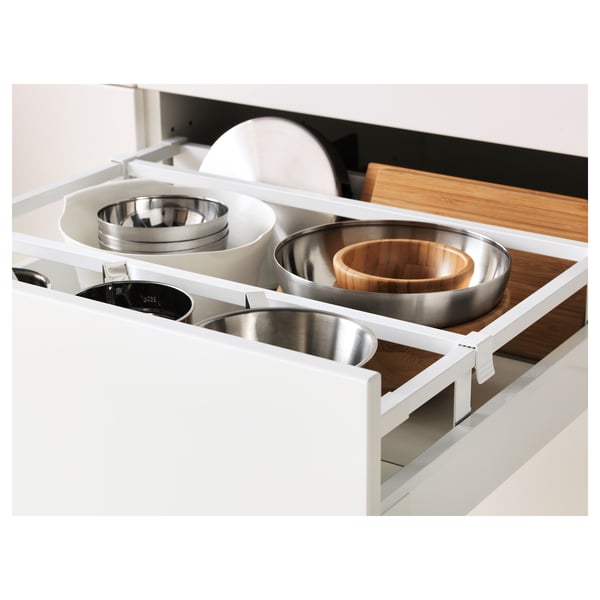 Open kitchen drawer with stacked pans and wooden bowl, organised with dividers.