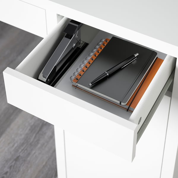 Open desk drawer with notebook, pen, and stationery, showing adjustable shelves and cable outlet.