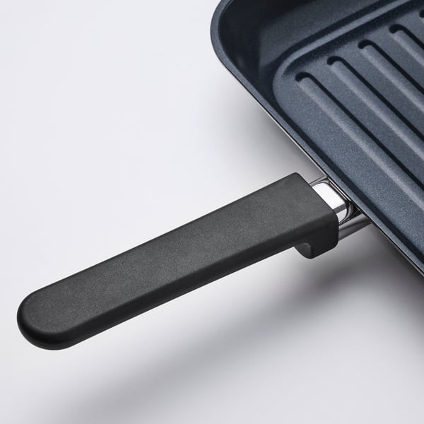 Close-up of MIDDAGSMAT grill pan handle, showcasing sturdy design and durable materials.