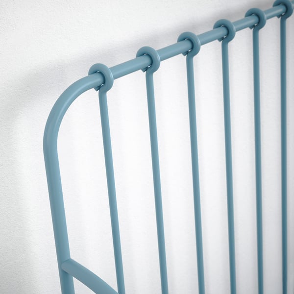 Modern, sturdy blue metal bed frame with vertical slats, guaranteeing safety and comfort, against white wall.