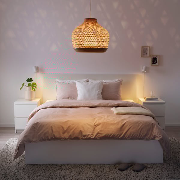 Cosy bedroom with handwoven bamboo pendant light, beige bedding, and minimal decor.