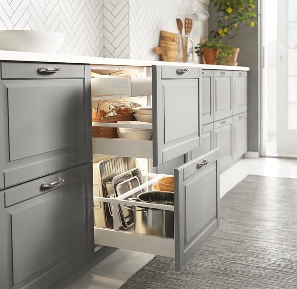 Modern kitchen with led-lit drawer, grey cabinets, and herringbone backsplash.