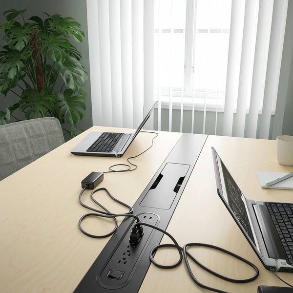 Conference table with built-in power outlet and cable management, facilitating easy device charging and organisation.