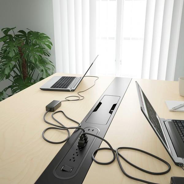 Conference table with integrated power strips, laptop connectors, and cable management.