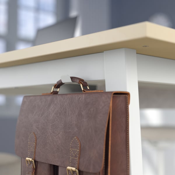 Brown leather bag hangs on white shelf with hook.