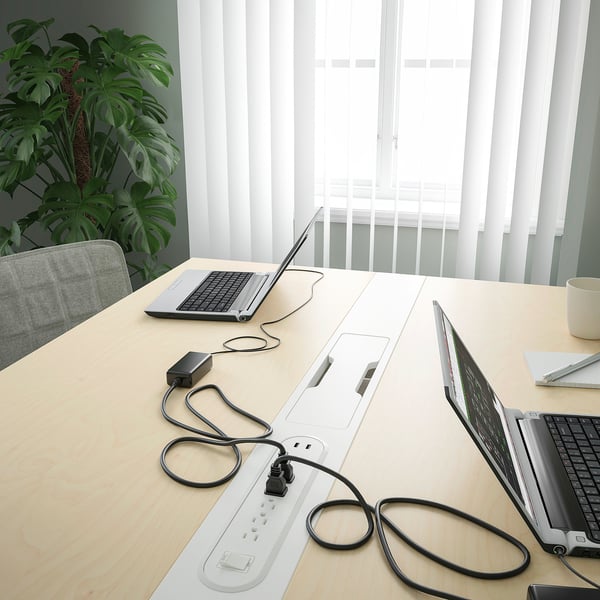 Conference table with laptops and cables, showcasing integrated cable management.