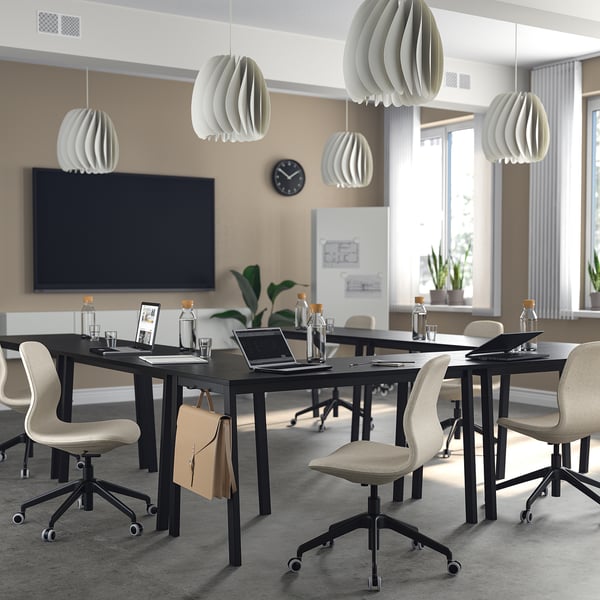 Modern office with MITTZON tables, chairs, pendant lamps, large screen, and clock.