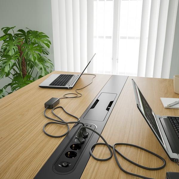 Conference table with built-in power outlets and cable management, perfect for charging devices during meetings.