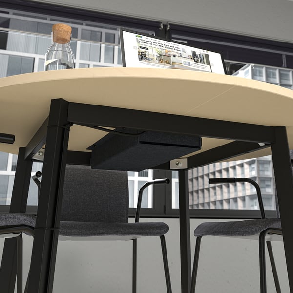 A round conference table with chairs, a bottle, and instructions on top, ideal for small group discussions and meetings.