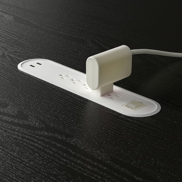 White table surface with built-in charging sockets and cable management tray.