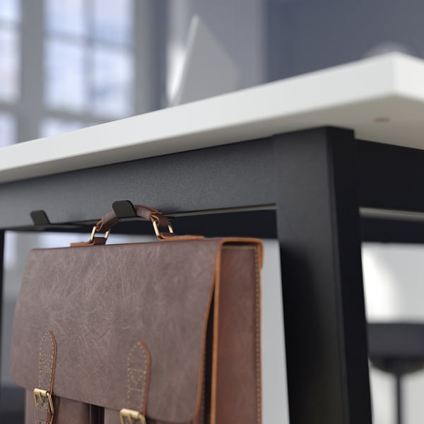 Brown leather bag hangs on black tables hook, offering a place to secure belongings during meetings.