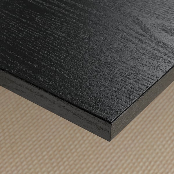 Dark wooden desk surface, smooth and polished, on textured beige flooring.
