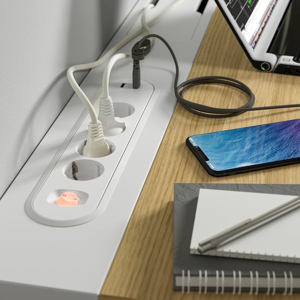 Desk with power outlets and cable management tray, smartphone charging, ergonomic design.