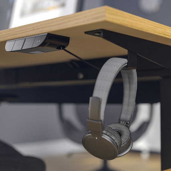Desk with motorised lift and memory settings for sit/stand, hanging headphones.