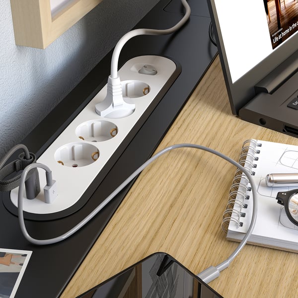 Modern black desk with laptop, cords, and open notebook.