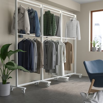 Modular coat rack with jackets, near plant and blue chair.