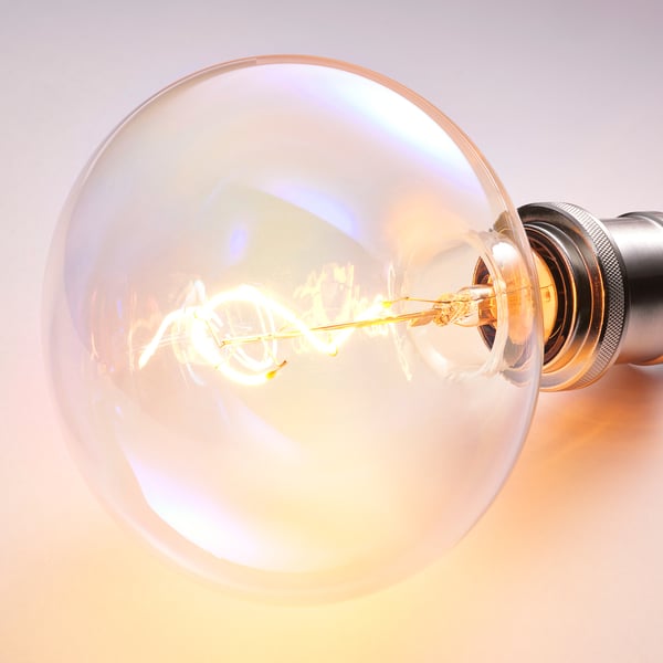 Close-up of a vibrant, glowing light bulb, featuring a spiral filament and double glass, illuminating warmly.