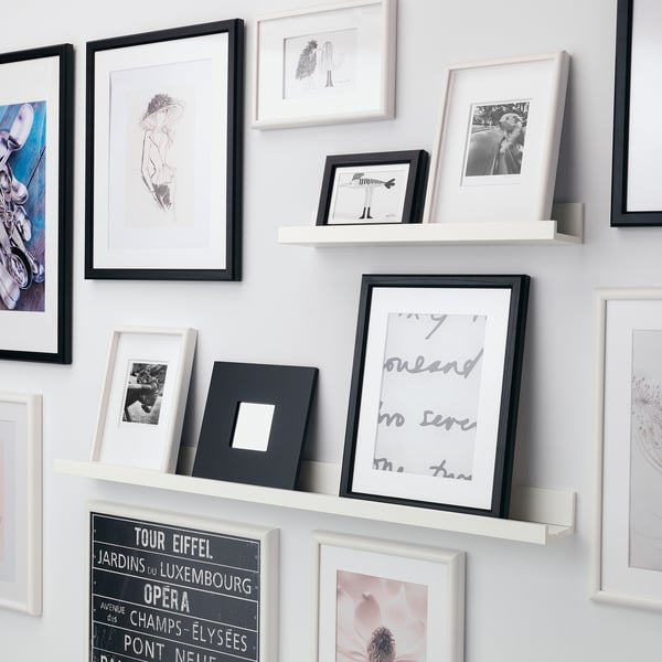 Wall display shelf with varied photo frames; personal items and art.