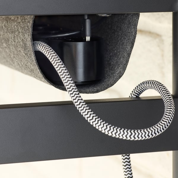 Black and white zigzag cable hangs from modern black desk.