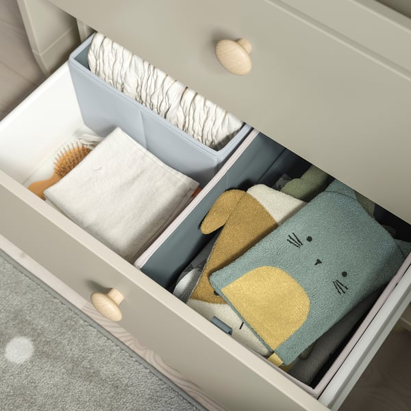 Open drawer reveals organised baby clothes and accessories.