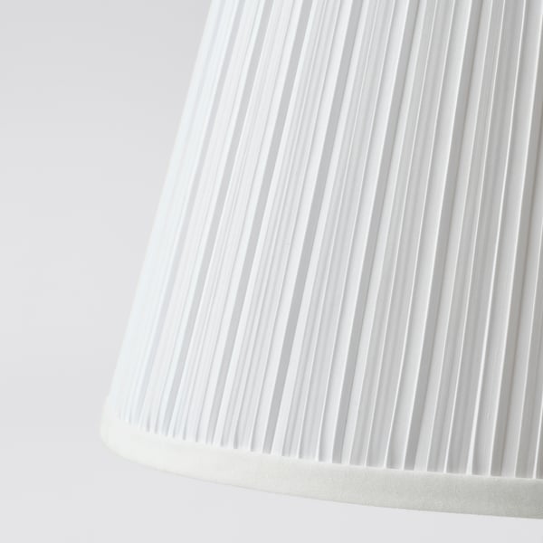 Close-up of a white pleated lamp shade. Light folds create a soft, diffused glow.